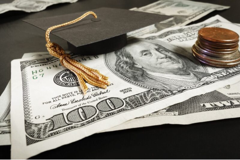 Paper money and coins with miniature graduate cap and tassel