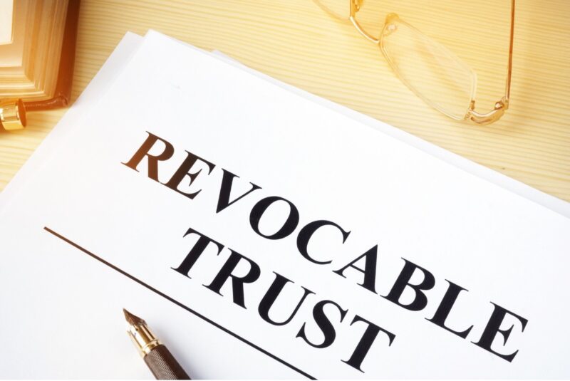 REVOCABLE TRUST on a paper on a desk with a pen and glasses