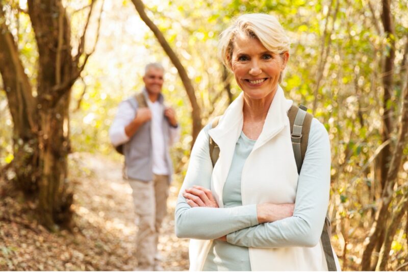 Active senior couple hiking on a wooded trail.